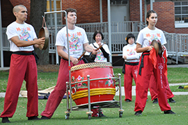 our musician/dancers in Asian bright red and white outfits perform on the Stetson Green.