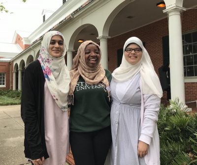 Group shot of the three women arm in arm in hijabs.