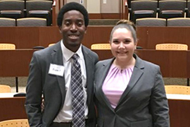The two students stand side by side in a courtroom