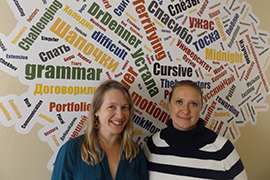 The two professors stand in front of a collection of English and Russian words written in bright primary colors.