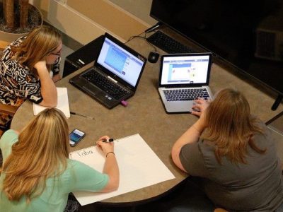 A shot looking down on three women working on computers at 2017 Hackathon.