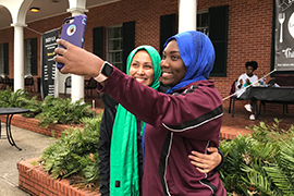 The two women smile for a selfie with their headscarves on.