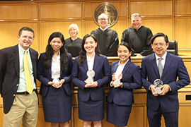Group photo of winning team in a courtroom with judges behind them