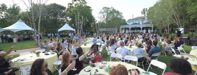 Panoramic shot of a bunch of tables and seated seniors in the large garden beside the president's home