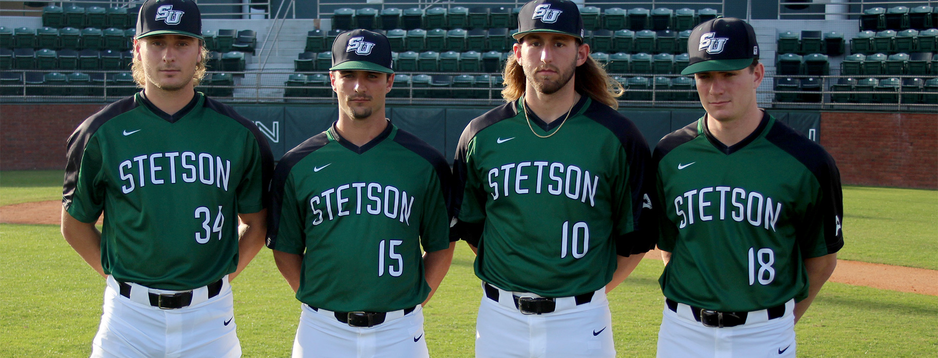 The four senior player stand side by side on the baseball field.