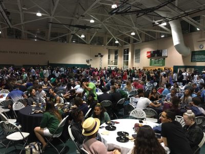 a wide crowd shot inside the Rinker Field House with people milling about and seated at tables.