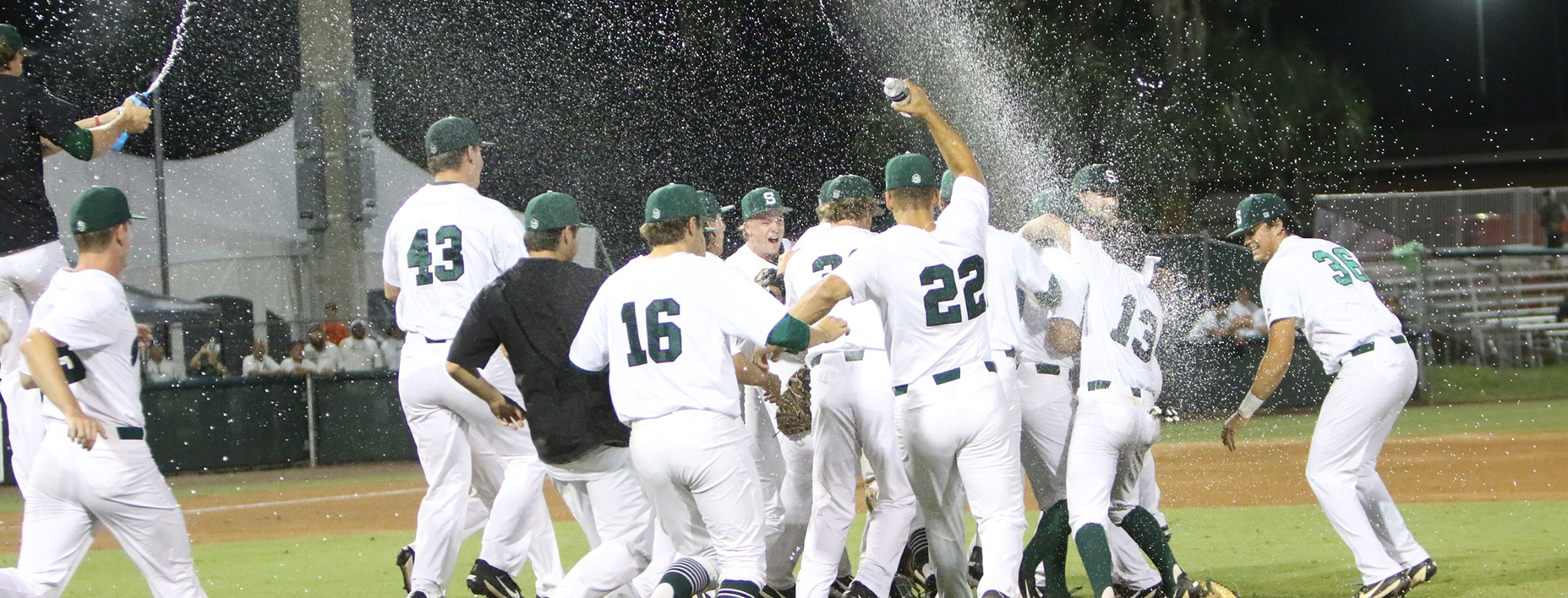 Players jump and spray water on the field after win.