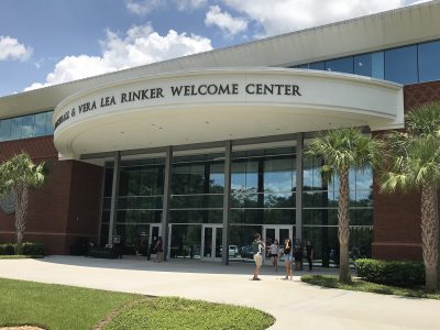 Exterior of Rinker Welcome Center with students milling about outside.
