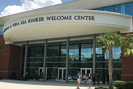 Exterior shot of Rinker Welcome Center with a handful of students milling about outside.