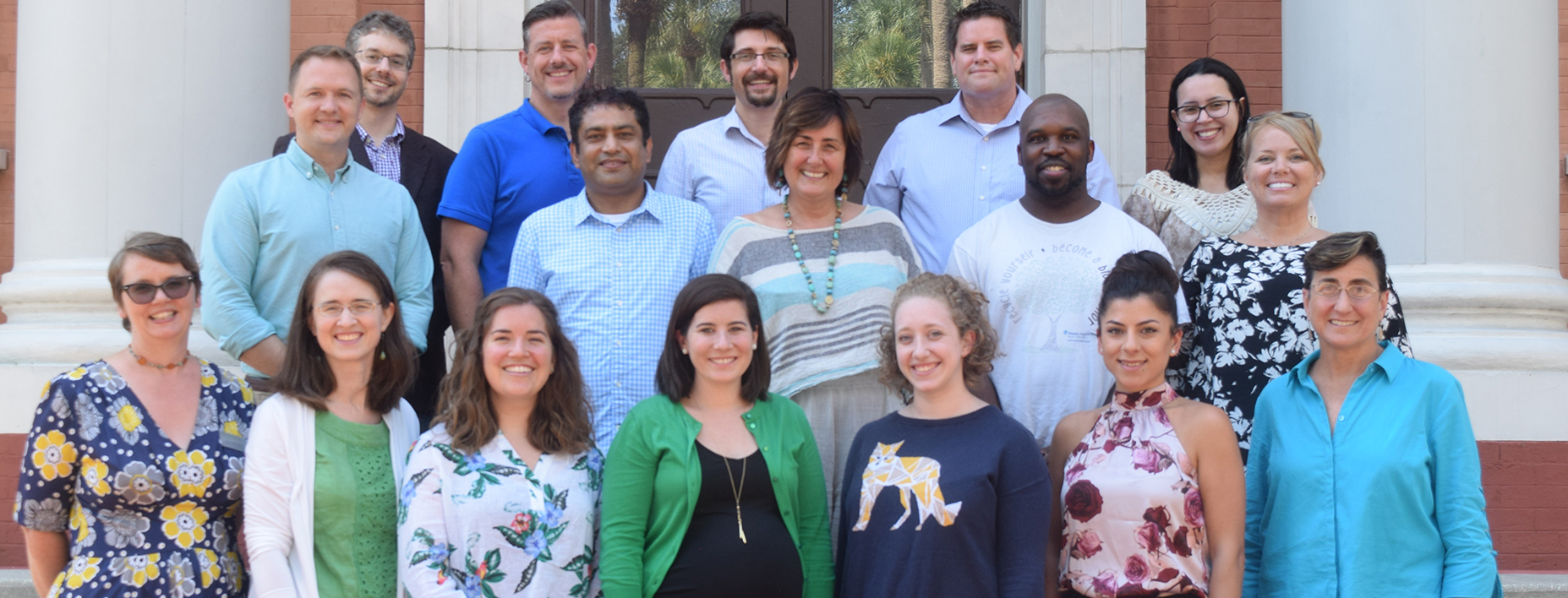 Three rows of new faculty members stand on the steps of Sampson Hall.