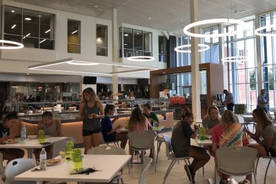 Students sit at tables eating in the expansive new Commons dining hall.