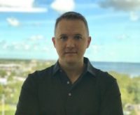 portrait outside with coastline behind him