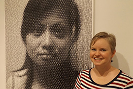 Hand Art Center director Tonya Curran poses beside “Mei,” one of the digital portraits in the exhibit “Anni Holm: The Immigration Project.”