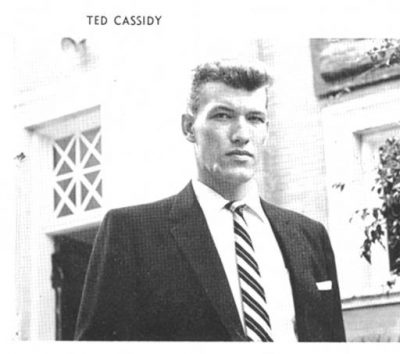 A young Ted Cassidy dressed in suit stands outside academic building at Stetson
