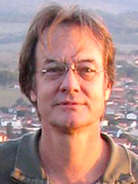 portrait outside with town in a valley behind him