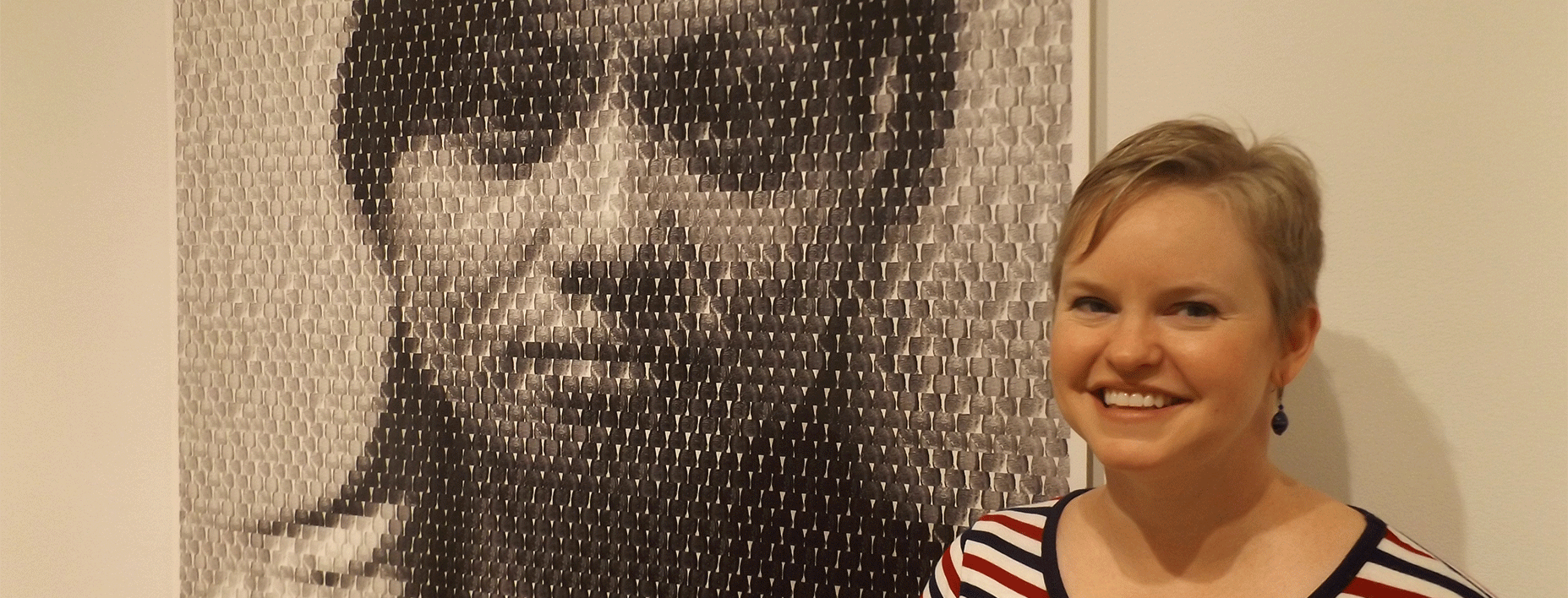 Hand Art Center director Tonya Curran poses beside “Mei,” one of the digital portraits in the exhibit “Anni Holm: The Immigration Project.”