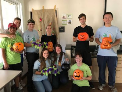 Students hold pumpkins and other decorations for Mostly Green Halloween