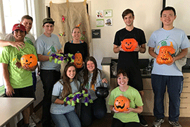 Students pose with pumpkins and other decorations for Mostly Green Halloween