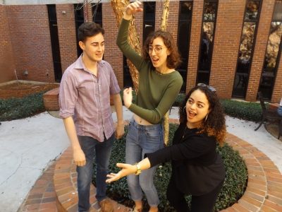 The three students mock perform in the courtyard in presser Hall.