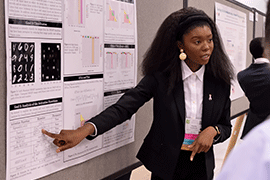 Heyley Gatewood points to a display board with technical information