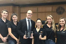 The group poses together in a courtroom with the award