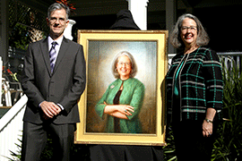 Artist Tom Reis and Wendy Libby stand with the portrait on stage