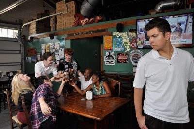 Man walks away from a table of people all drinking and having fun in a bar