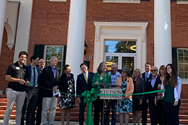 long line of people holding green ribbon; Wendy cutting it