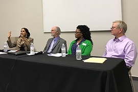 the four professors are seated at a panel discussion inside the museum.