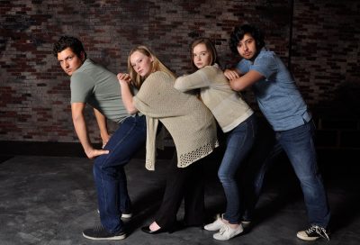 The four actors lean into each other for a group shot