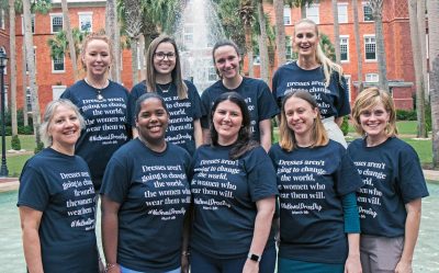 Nine women stand in front of the Palm Court fountain with t-shirts for National Dress Day.
