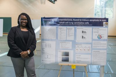 A student stands next to a poster detailing her research at Stetson Showcase 2016.