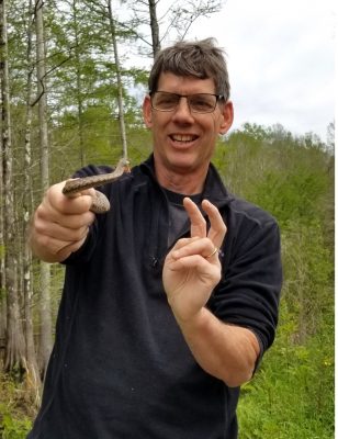 Professor holds a snake in the woods