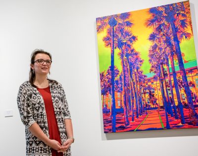 Sarah Hargest stands beside Palm Court painting