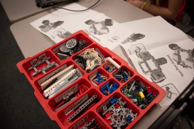 A plastic bin filled with small plastic parts and instructions for building the robotic rover.