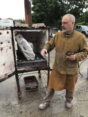 Sculptor stands in front of a warming box with mold for Stetson hat