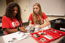 Two teenage girls assemble a robotics model