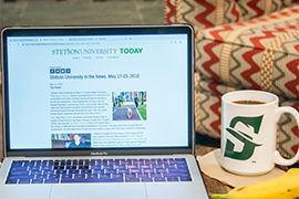 a computer screen that shows "Stetson University in the News" with a cup of coffee and a banana