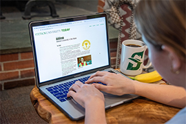 The screen of a laptop with Stetson in the News on the screen and a woman with her hands on the keyboard