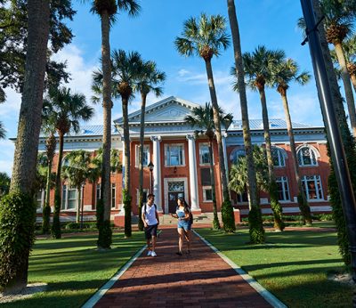 2 students walk in palm court