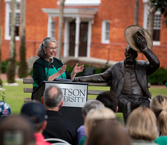 President Libby speaks at the dedication for the John B statue, in the background