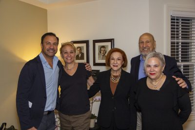 Group shot in a living room with portraits on the wall behind them of their parents.