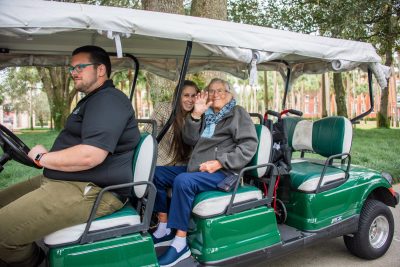 The two women are seated in a nice golf cart with Sam Friedman at the wheel.