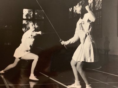 Eloise lunges forward with sword as another female tries to defend herself in fencing