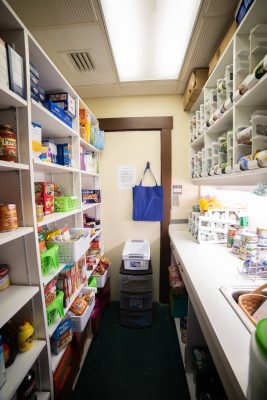 inside of Hatter Food Pantry, the size of a walk-in closet, with shelves on both sides.