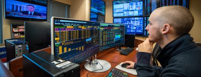 A student works at a computer filled with financial info in the RGIP Trading room