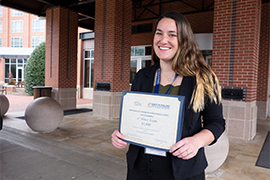 portrait outside holding award certificate