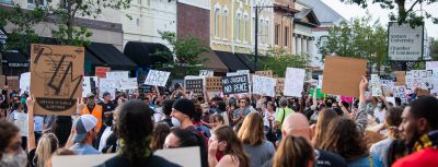 a crowd holds signs in downtown DeLand