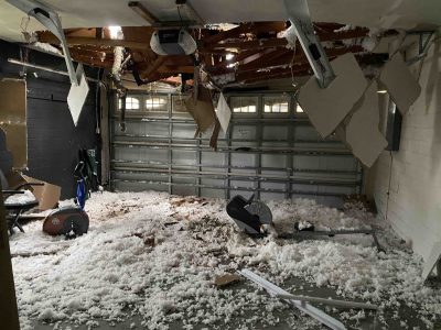 Garage is covered with debris and ceiling has a hole in it from tornado