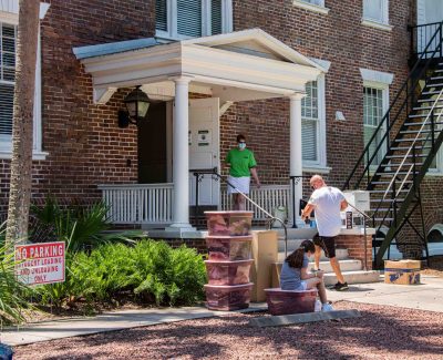 A father carries belongings into a residence hall.